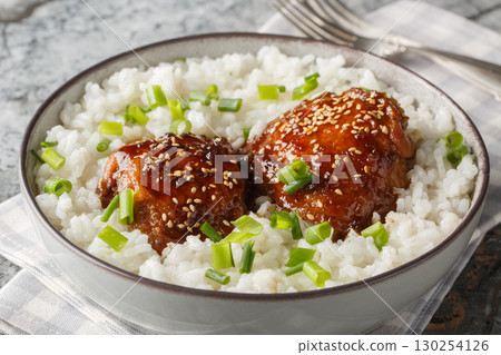Japanese inspired braised chicken dish made with chicken thighs that simmer in a shoyu based sauce with white rice closeup on the plate. Horizontal 130254126