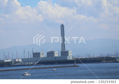 雲彩、朦朧的藍天、山脈、沿海工廠、藍色海面和船隻的風景 130254363