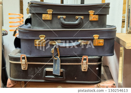 Stack of vintage suitcases with metal clasps on display in a secondhand shop. Eco-conscious shopping, reuse revolution, sustainable travel, waste reduction 130254613