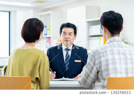 Consultant explaining to middle-aged couple Consultant explaining to middle-aged couple 130256013