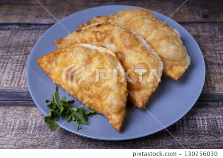 Chebureki with meat. A flat pie deep-fried until crispy. A traditional popular dish. Selective focus, close-up. Chebureki with meat. A flat pie deep-fried until crispy. A traditional popular dish. Selective focus, close-up. 130256030