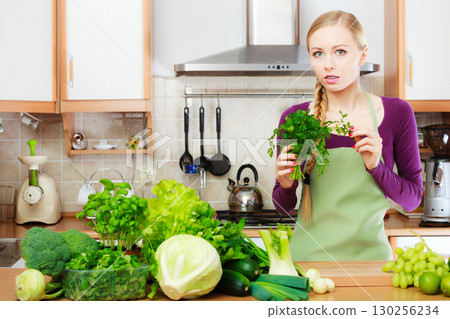 Woman housewife in kitchen with green vegetables Woman housewife in kitchen with green vegetables 130256234