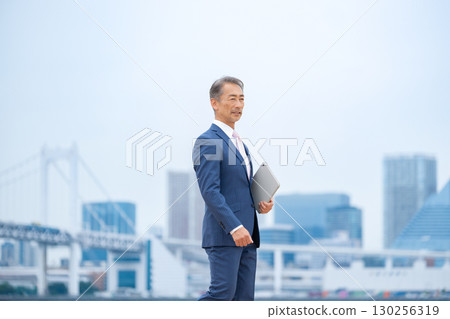Businessman walking through buildings Businessman walking through buildings 130256319