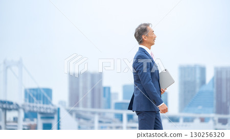Businessman walking through buildings Businessman walking through buildings 130256320