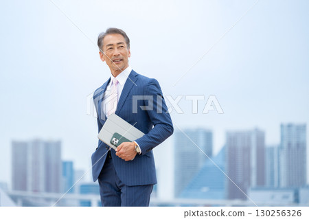 步行穿過建築物的商人 130256326