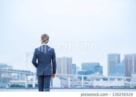 步行穿過建築物的商人 130256329