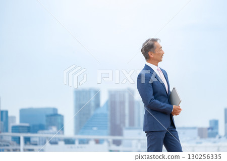 Businessman walking through buildings 130256335