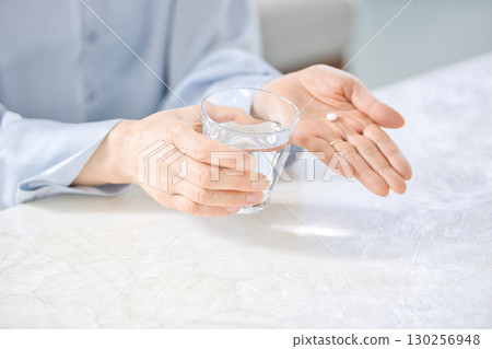 Hands of a middle-aged woman taking medicine Hands of a middle-aged woman taking medicine 130256948