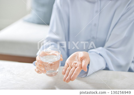 Hands of a middle-aged woman taking medicine Hands of a middle-aged woman taking medicine 130256949