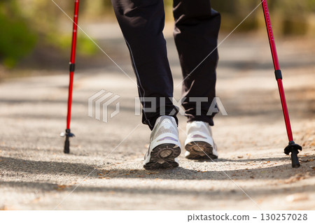 Nordic walking. Female legs hiking in the park. 130257028