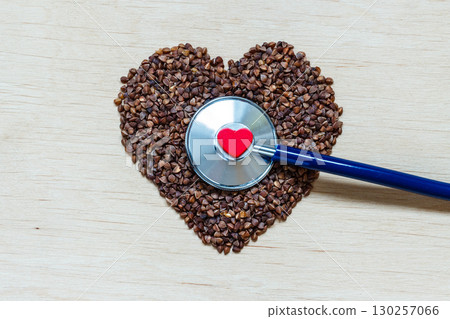 buckwheat groats heart shaped on wooden surface. buckwheat groats heart shaped on wooden surface. 130257066