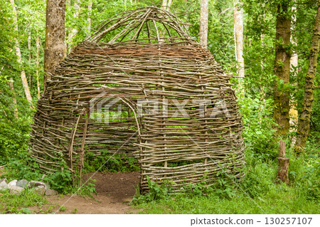 Small cottage made of wooden sticks in woods 130257107
