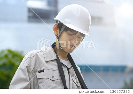 穿著工作服的年輕商人在建築工地上看著平板電腦 130257225