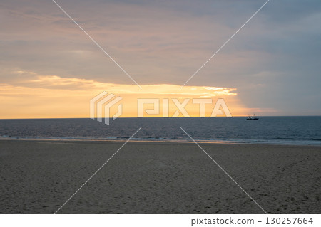 Sunset on the beach near beautiful sea in the evening. Boat and yellow sunlight. Vacation in Ostend, Belgien. Sunset on the beach near beautiful sea in the evening. Boat and yellow sunlight. Vacation in Ostend, Belgien. 130257664