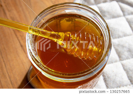 Honey glass jar with honeycomb and yellow spoon stay on the wood table and napkin. 130257665