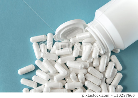 Much medical pills and tabletts in white plastic bottle on the blue paper background. Healthcare concept. 130257666