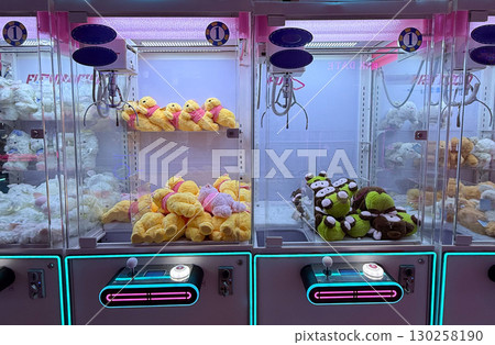 Plush toys inside claw machines in arcade hall. Leisure, entertainment, and playful atmosphere for childhood memories. 130258190
