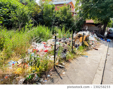 Pile of garbage and plastic waste among green grass. Pollution, environmental damage, and ecological issues in urban surroundings. Pile of garbage and plastic waste among green grass. Pollution, environmental damage, and ecological issues in urban surroundings. 130258233