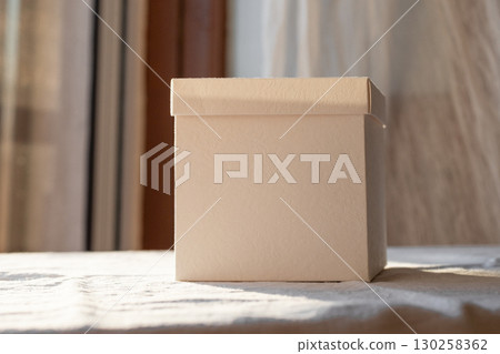 Sunlit White Box Mockup on a Table Near a Window During Sunset Hours Sunlit White Box Mockup on a Table Near a Window During Sunset Hours 130258362