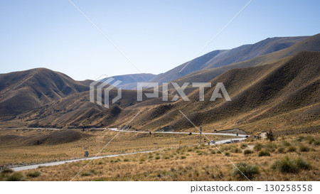 Highway running through hilly valley with no trees, Lindis Pass, New Zealand 130258558
