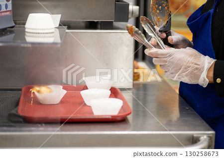 A woman's hands serving food at the tasting corner of a supermarket A woman's hands serving food at the tasting corner of a supermarket 130258673