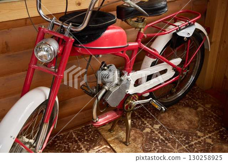 A vintage red motorized bicycle with striking white accents, ideal for enthusiasts 130258925