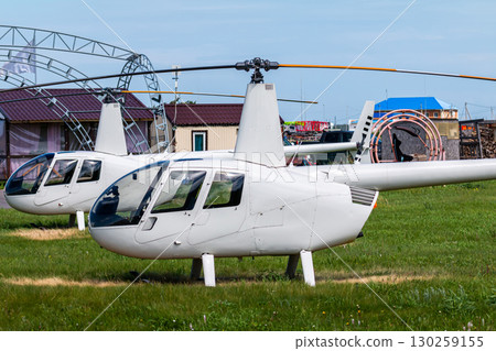 Two private small white helicopters at the airfield 130259155