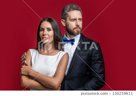 Formal couple. Couple in formal wear. Man and woman in luxury suit. Elegant style date. Romantic woman with elegant man isolated on red. Couple in love. Valentines day occasion. Special occasion 130259611