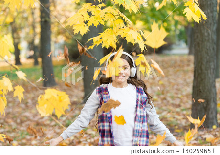 Face your happy mood. Little child have fun with autumn leaves. Happy childhood. Happy small girl listen to music in autumn park. Syncing your happy moments Face your happy mood. Little child have fun with autumn leaves. Happy childhood. Happy small girl listen to music in autumn park. Syncing your happy moments 130259651