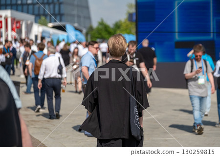 Back view of a group of people walking outdoors at an event Back view of a group of people walking outdoors at an event 130259815