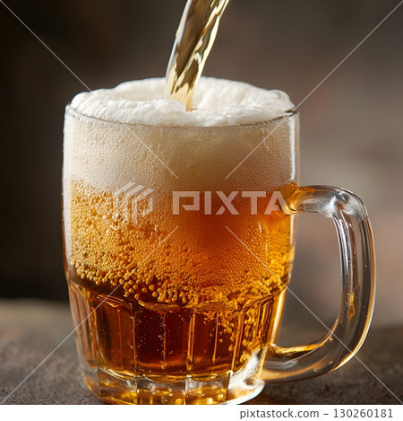 Close-up of frothy beer being poured into a large glass mug, 130260181