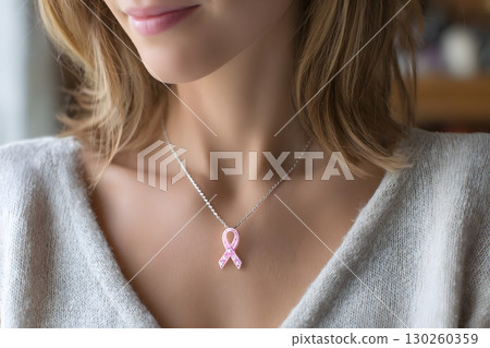 woman showing pink ribbon pendant necklace close up 130260359
