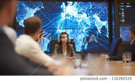 female leader in boardroom with logistics network on big screen 130260526