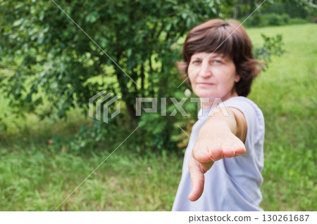 Mature woman doing pilates at public park, focus on hand. Healthy lifestyle Mature woman doing pilates at public park, focus on hand. Healthy lifestyle 130261687