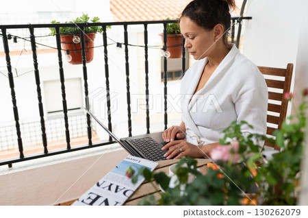 Woman in Casual Attire Working on Laptop at a Home Balcony Woman in Casual Attire Working on Laptop at a Home Balcony 130262079