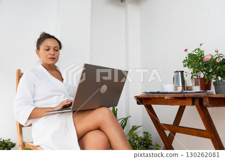 Woman in White Robe with Laptop Enjoying Relaxing Outdoor Workspace Woman in White Robe with Laptop Enjoying Relaxing Outdoor Workspace 130262081