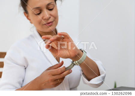 Woman Adjusting Smartwatch While Sitting Indoors in a Relaxed Setting Woman Adjusting Smartwatch While Sitting Indoors in a Relaxed Setting 130262096