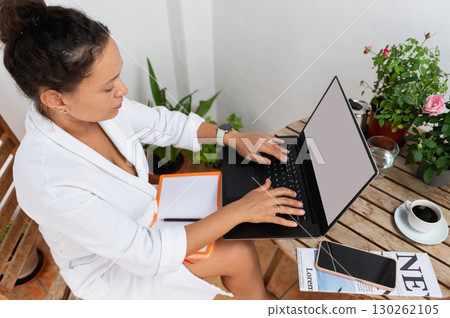Woman Working on Laptop at Outdoor Table with Coffee and Plants Woman Working on Laptop at Outdoor Table with Coffee and Plants 130262105