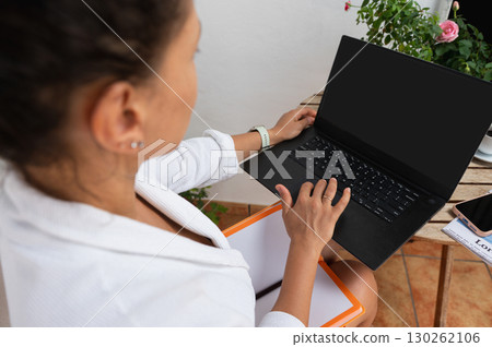 Woman Working Remotely on Laptop at Outdoor Workspace Woman Working Remotely on Laptop at Outdoor Workspace 130262106