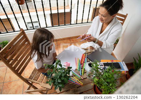 Mother and Daughter Drawing Together on a Balcony Table 130262204