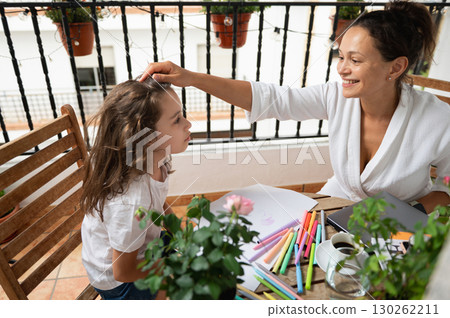 Mother Checking Daughter's Drawing During Creative Art Session at Home Balcony Mother Checking Daughter's Drawing During Creative Art Session at Home Balcony 130262211
