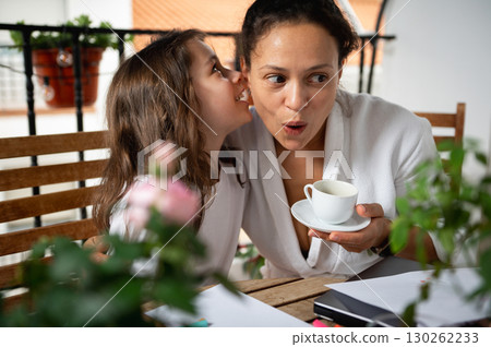 Mother and Daughter Sharing a Secretive Moment Over Morning Coffee on Balcony 130262233