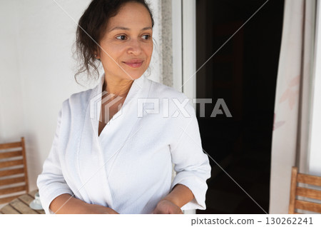 Peaceful Woman in White Robe Relaxing on a Sunny Balcony Peaceful Woman in White Robe Relaxing on a Sunny Balcony 130262241