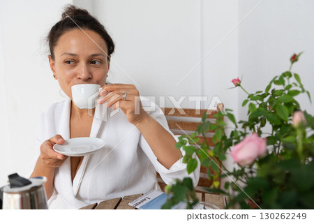 Woman Enjoying Coffee Outdoors Near Flowering Plants in Relaxed Atmosphere 130262249