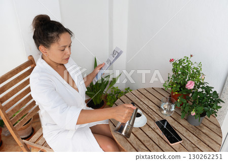 Woman Relaxing with Coffee and Reading Newspaper on Outdoor Balcony Woman Relaxing with Coffee and Reading Newspaper on Outdoor Balcony 130262251