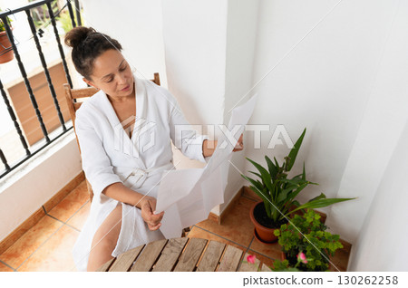 Woman Relaxing on a Balcony While Reading a Document Woman Relaxing on a Balcony While Reading a Document 130262258