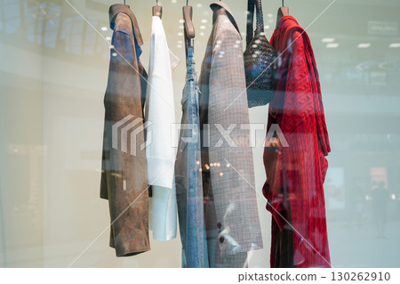 A row of stylish clothes and accessories hanging in a modern store display behind glass A row of stylish clothes and accessories hanging in a modern store display behind glass 130262910