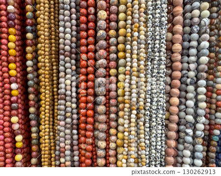 A display of assorted natural stone beads in various earthy tones arranged in strands A display of assorted natural stone beads in various earthy tones arranged in strands 130262913