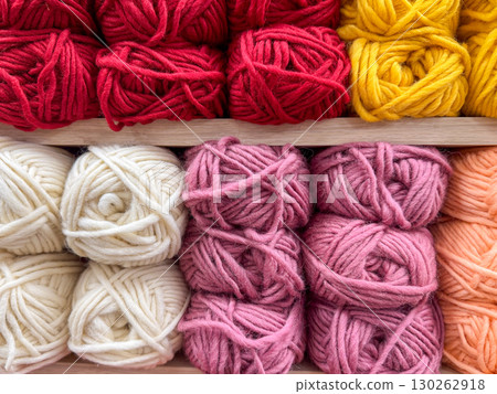 A close-up view of red, yellow, pink, and white yarn balls stacked on shelves A close-up view of red, yellow, pink, and white yarn balls stacked on shelves 130262918
