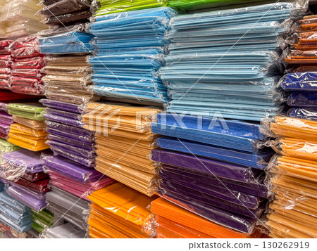 Stacks of multicolored craft paper wrapped in plastic and organized on store shelves 130262919